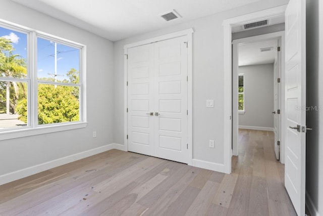 unfurnished bedroom featuring a closet, multiple windows, and light hardwood / wood-style flooring