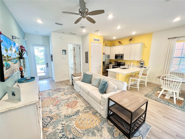 living room featuring sink, ceiling fan, and light wood-type flooring