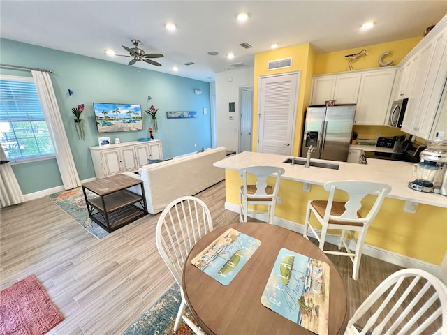 dining room featuring light hardwood / wood-style floors, ceiling fan, and sink