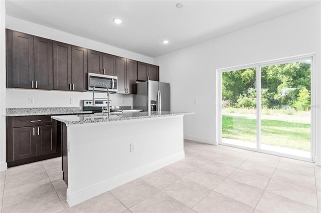 kitchen featuring light tile flooring, appliances with stainless steel finishes, an island with sink, and a wealth of natural light