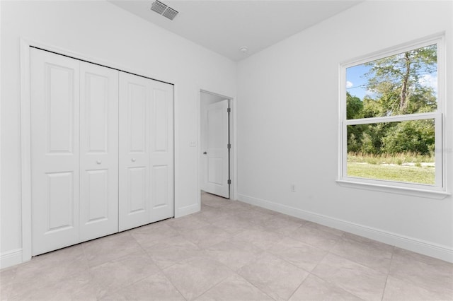 unfurnished bedroom featuring a closet, multiple windows, and light tile floors