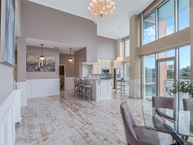 dining room featuring a high ceiling, ornamental molding, and a notable chandelier