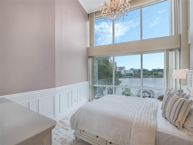 bedroom featuring a water view and an inviting chandelier