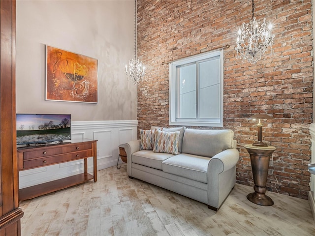 sitting room with a high ceiling, light wood-type flooring, and an inviting chandelier