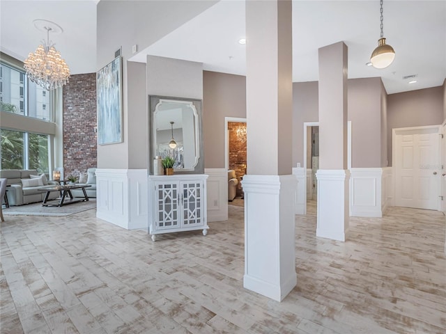 interior space featuring ornate columns, a high ceiling, a notable chandelier, pendant lighting, and a kitchen island