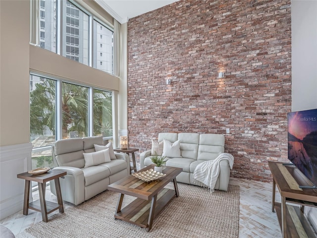 living room with a towering ceiling and brick wall