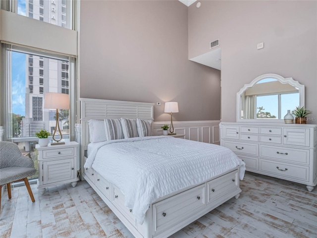 bedroom featuring light wood-type flooring and a towering ceiling