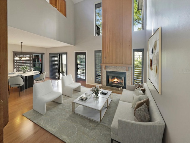 living room with a tile fireplace, a chandelier, a towering ceiling, and hardwood / wood-style flooring