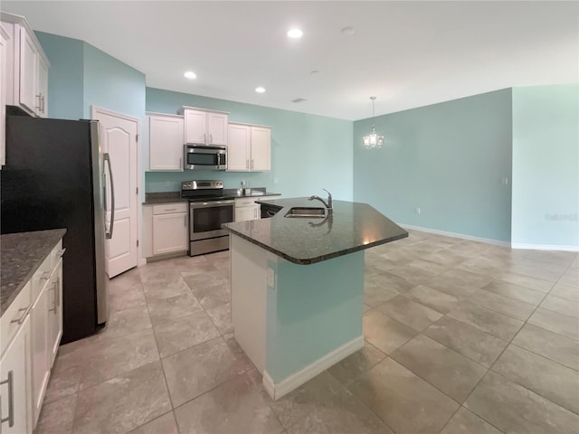 kitchen featuring hanging light fixtures, light tile flooring, appliances with stainless steel finishes, sink, and an island with sink