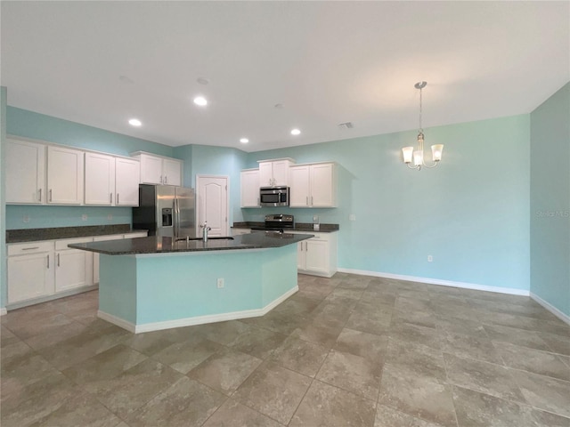 kitchen with appliances with stainless steel finishes, pendant lighting, a center island with sink, and light tile floors