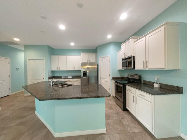 kitchen with appliances with stainless steel finishes, a center island with sink, dark stone counters, sink, and light tile floors