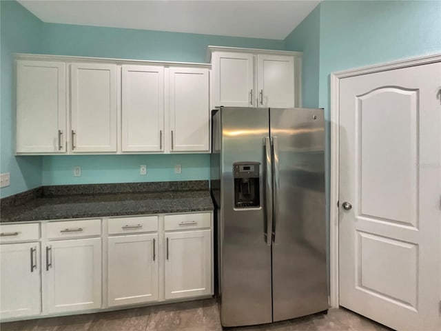 kitchen featuring dark stone countertops, tile flooring, white cabinetry, and stainless steel fridge