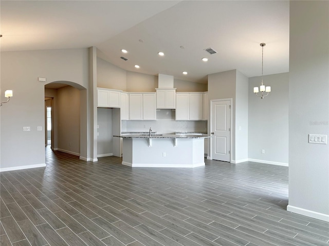 kitchen featuring tasteful backsplash, white cabinetry, an island with sink, a chandelier, and dark hardwood / wood-style flooring