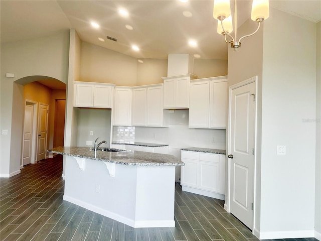 kitchen featuring an island with sink, sink, and white cabinets