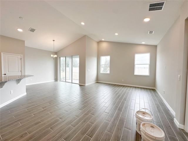 unfurnished living room featuring lofted ceiling and a chandelier