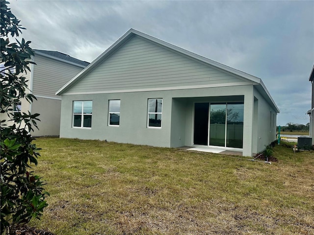 rear view of property featuring cooling unit and a lawn