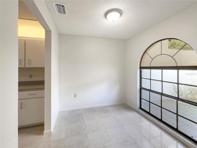 unfurnished room with a textured ceiling and light tile patterned floors