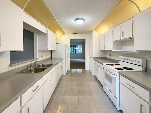 kitchen with a textured ceiling, sink, white cabinets, white appliances, and light tile patterned floors