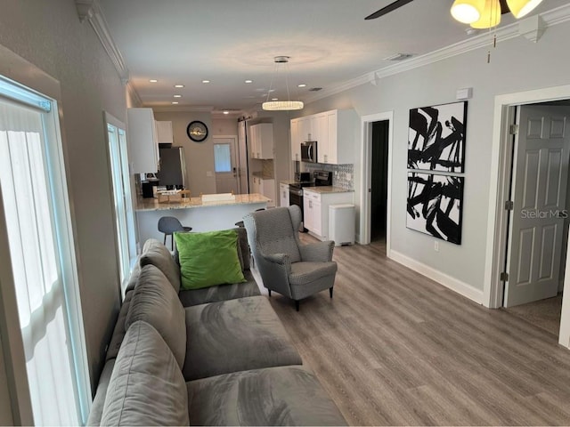 living room featuring ornamental molding, light hardwood / wood-style floors, and ceiling fan