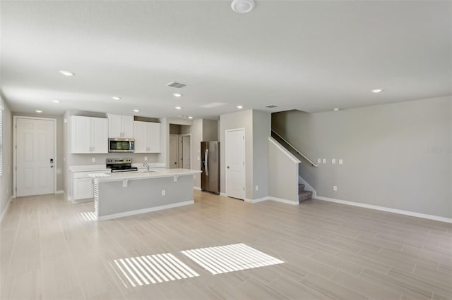 kitchen with sink, stainless steel appliances, a kitchen breakfast bar, an island with sink, and white cabinets