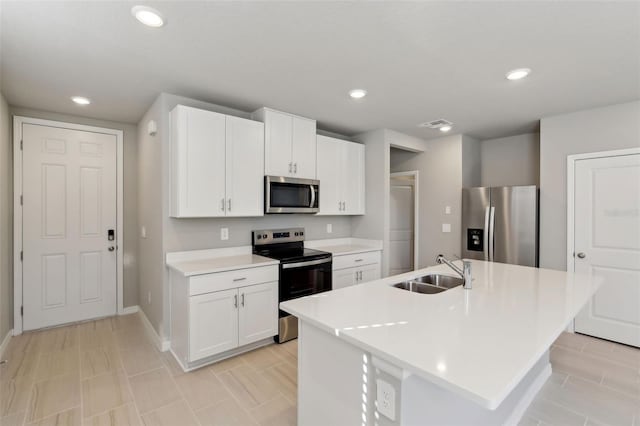 kitchen featuring stainless steel appliances, white cabinetry, a center island with sink, and sink