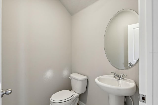 bathroom featuring toilet, sink, and vaulted ceiling