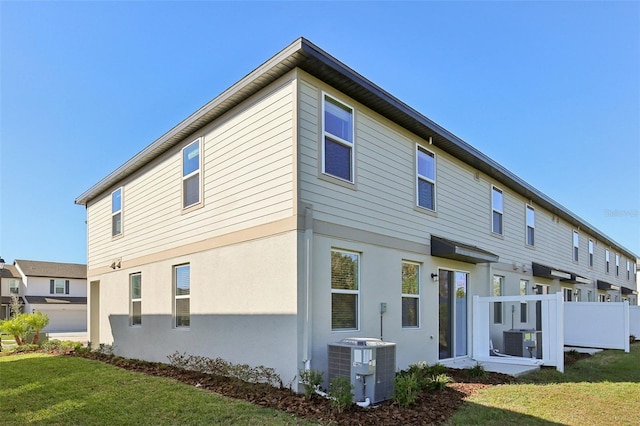 rear view of house with cooling unit and a lawn