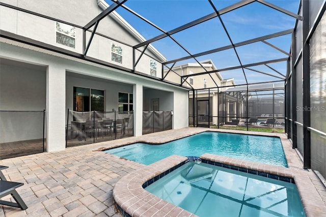 view of pool featuring glass enclosure, an in ground hot tub, and a patio