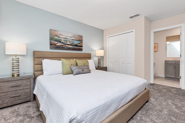 bedroom with light colored carpet, a closet, and ensuite bathroom