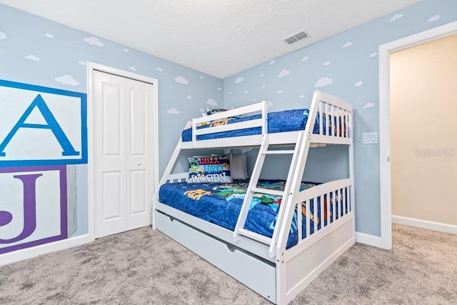 bedroom with a textured ceiling, carpet floors, and a closet