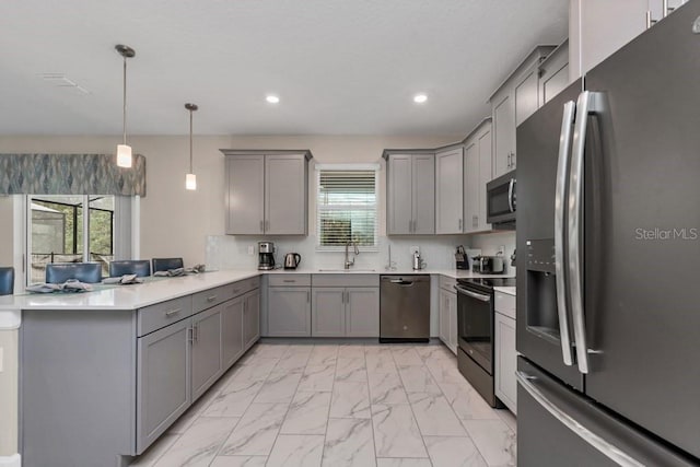 kitchen featuring kitchen peninsula, stainless steel appliances, sink, gray cabinets, and hanging light fixtures