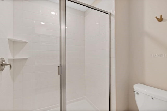 bathroom featuring an enclosed shower and toilet