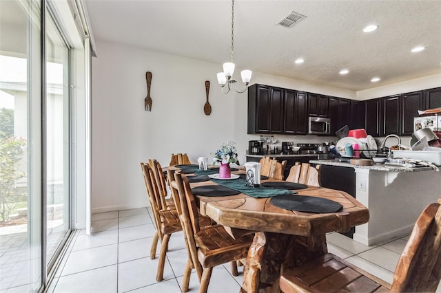 tiled dining area featuring a chandelier and a textured ceiling