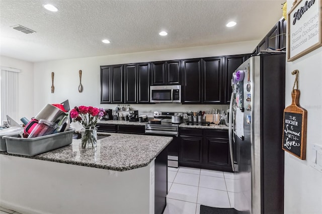 kitchen featuring stainless steel appliances, a textured ceiling, and light tile floors