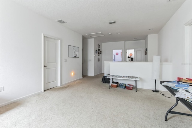 miscellaneous room featuring a textured ceiling and light colored carpet