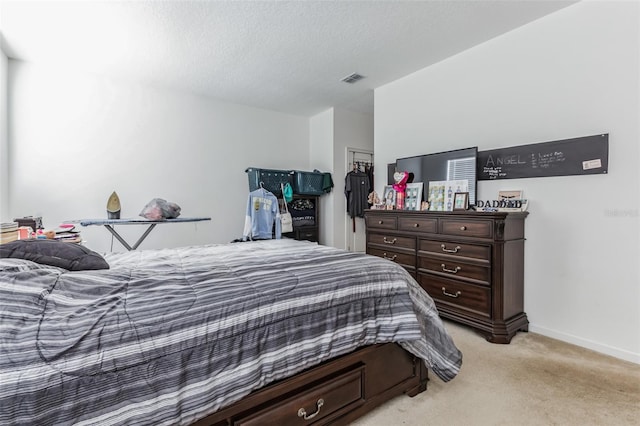 bedroom featuring a textured ceiling and light colored carpet