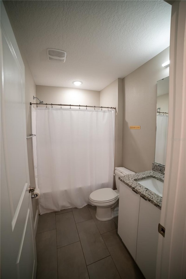 bathroom with vanity, a textured ceiling, tile patterned flooring, toilet, and curtained shower