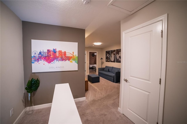 hallway with light colored carpet and a textured ceiling