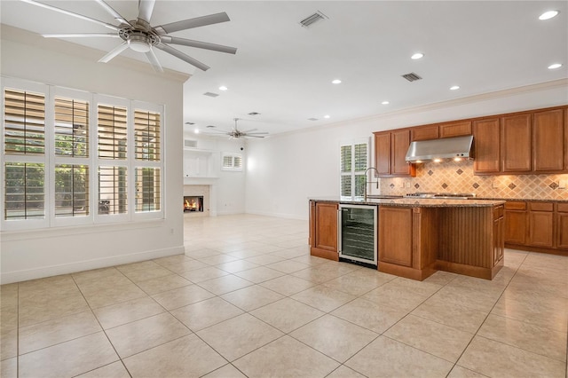 kitchen featuring a center island, wine cooler, light tile floors, tasteful backsplash, and ceiling fan