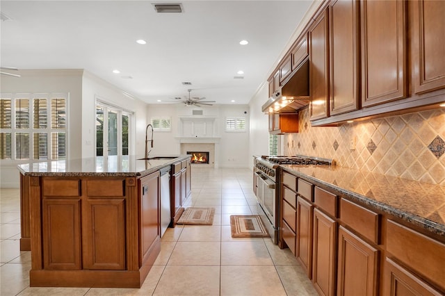 kitchen featuring a kitchen island with sink, light tile flooring, stainless steel appliances, ceiling fan, and exhaust hood