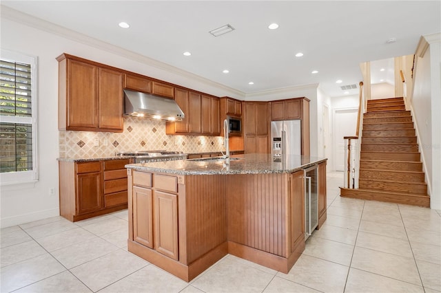 kitchen with stainless steel appliances, light tile flooring, tasteful backsplash, a kitchen island with sink, and sink