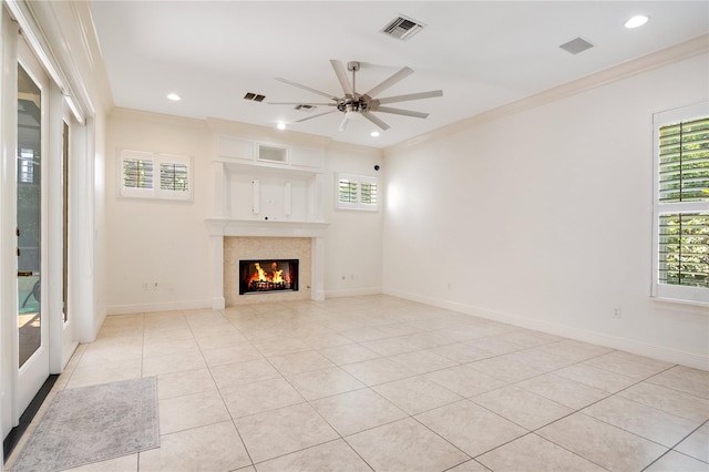 unfurnished living room with a premium fireplace, ceiling fan, plenty of natural light, and ornamental molding