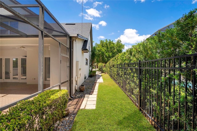 view of yard with a patio, ceiling fan, and glass enclosure