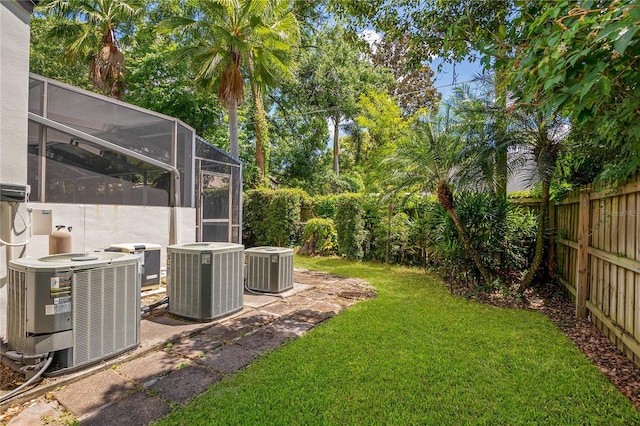 view of yard featuring central air condition unit, glass enclosure, and a patio