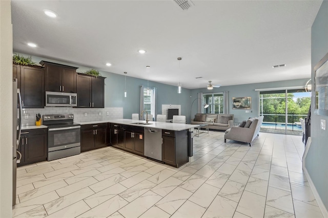 kitchen with dark brown cabinetry, sink, kitchen peninsula, and appliances with stainless steel finishes