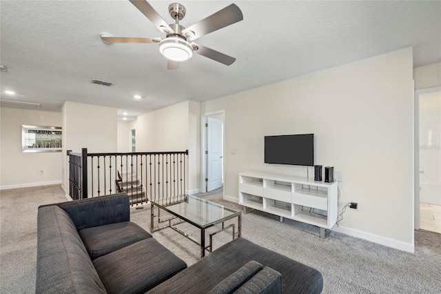 carpeted living room featuring ceiling fan and a textured ceiling