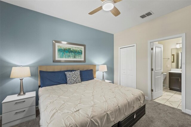 carpeted bedroom with ceiling fan, ensuite bath, and a closet