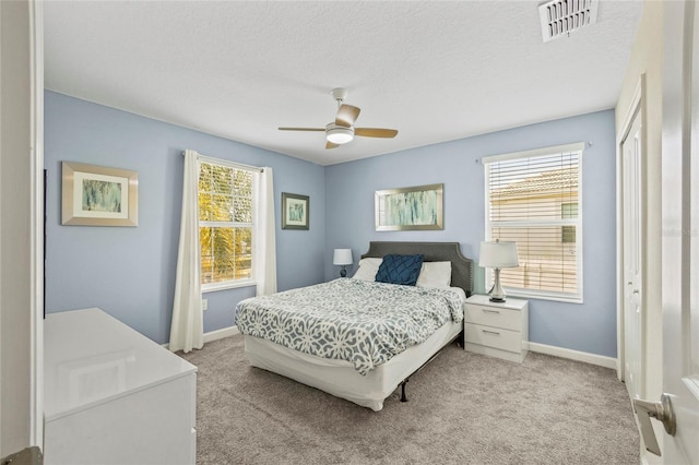 carpeted bedroom with ceiling fan and a textured ceiling