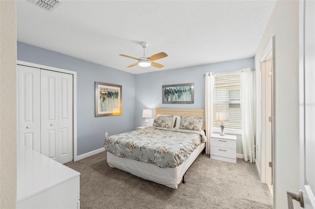 carpeted bedroom with ceiling fan, a closet, and a textured ceiling