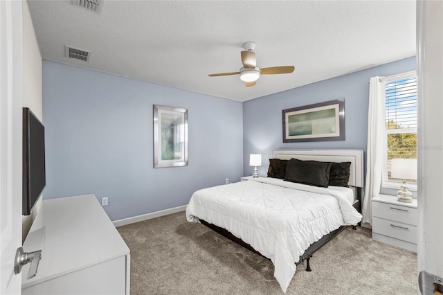 bedroom with ceiling fan, light carpet, and a textured ceiling